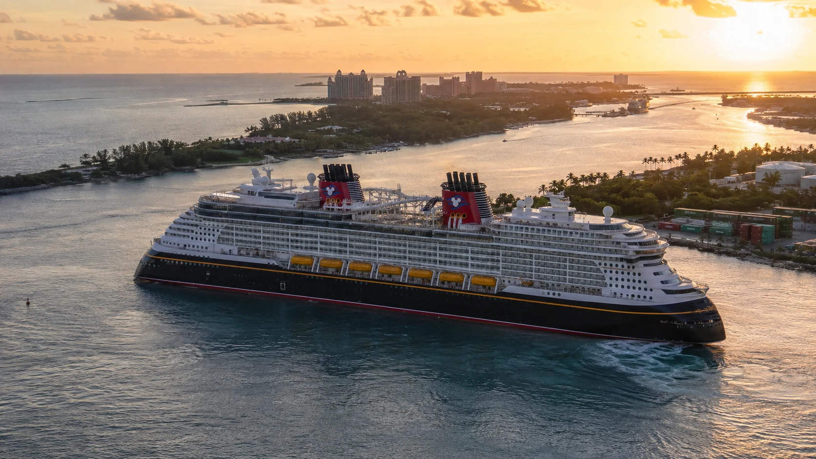 Disney Destiny sailing past a tropical island at sunrise