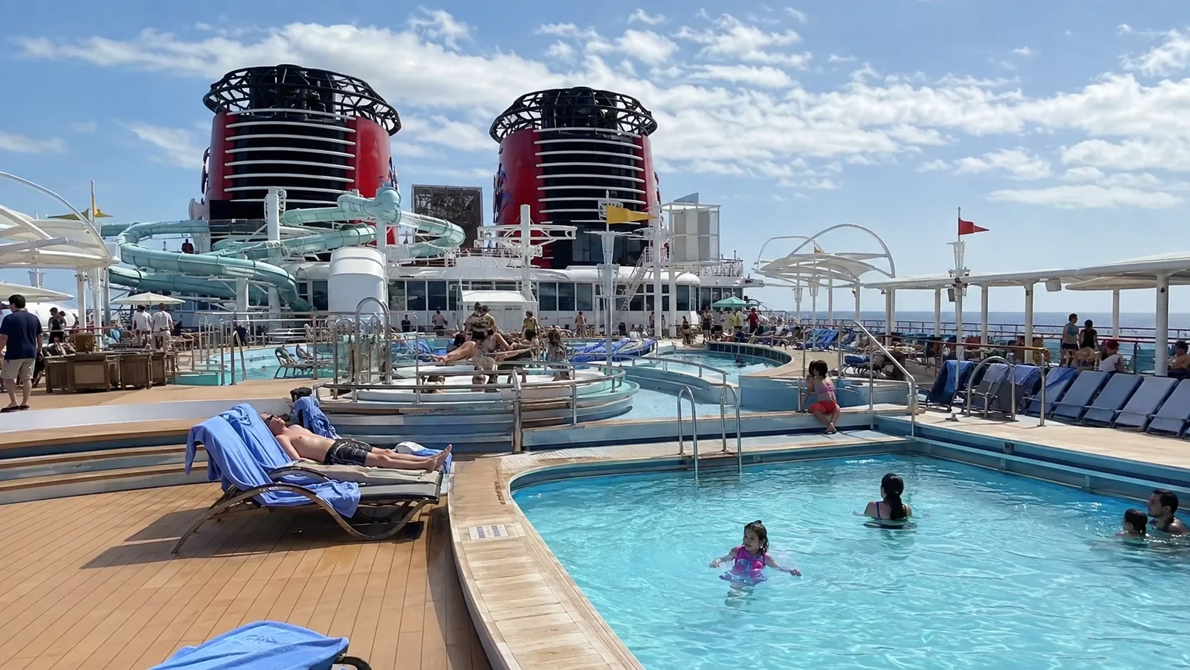 Families swimming on the Disney Destiny pool deck