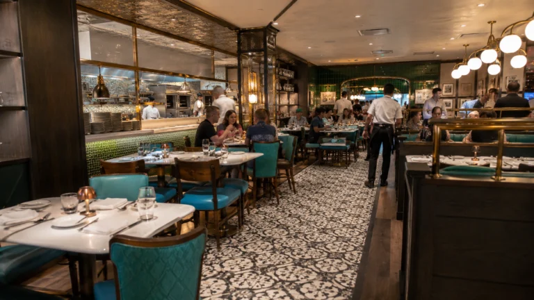 Teal dining chairs and open kitchen inside Emeril's Bistro