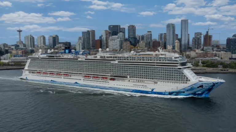 Norwegian Bliss sailing near a coastal city