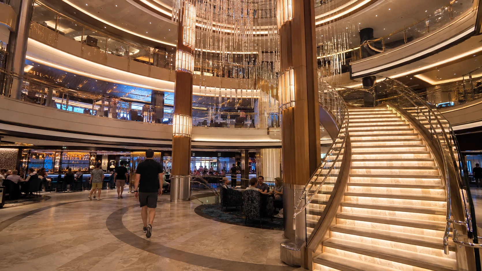 Curved staircase and chandelier in 678 Ocean Place aboard Norwegian Encore
