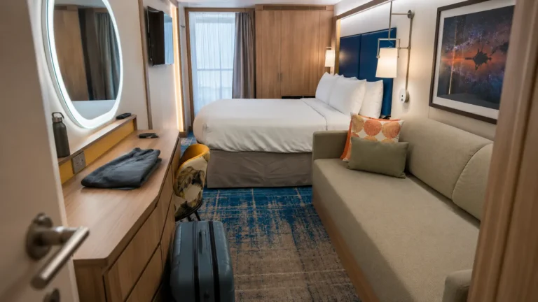 Cruise stateroom with a bed, sofa and ocean-view window